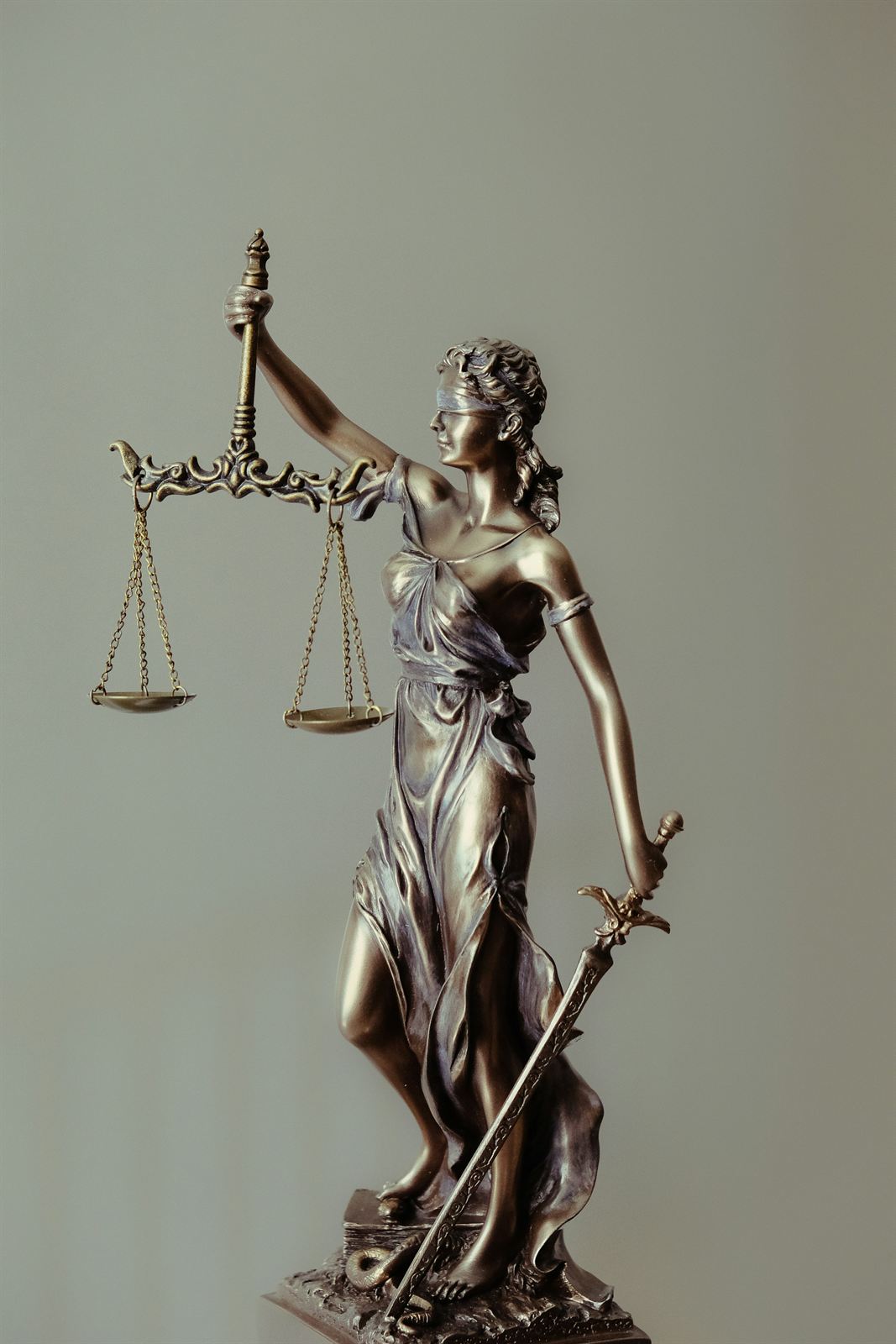 A bronze statue of Lady Justice holding a set of scales
