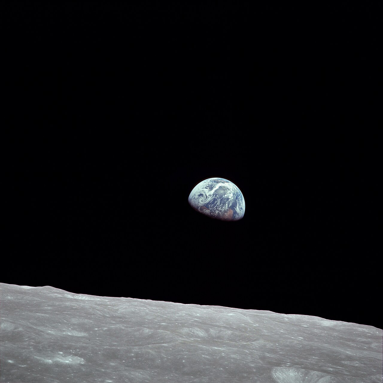 Earth rising over the lunar horizon against black space